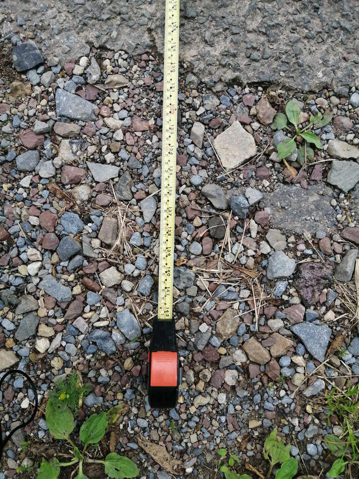 A tape measure that shows 361cm (142in) on the ground next to a road