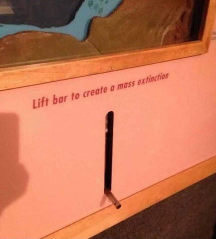 Some kind of installation in a museum with a flip switch titled 'Lift bar to create a mass extinction' in red letters above the switch